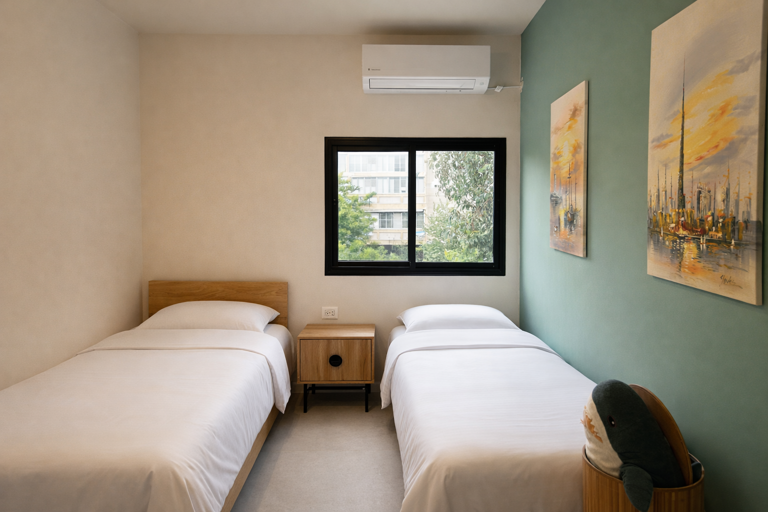 The second bedroom: two beds, a sage-green wall and harbor paintings