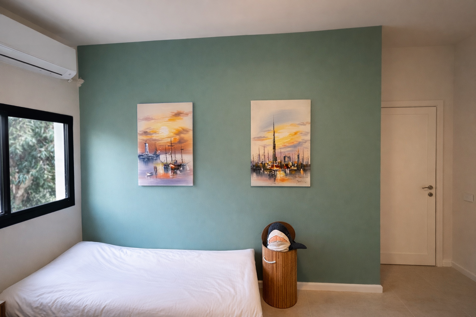 A sage-green wall and two paintings in the second bedroom