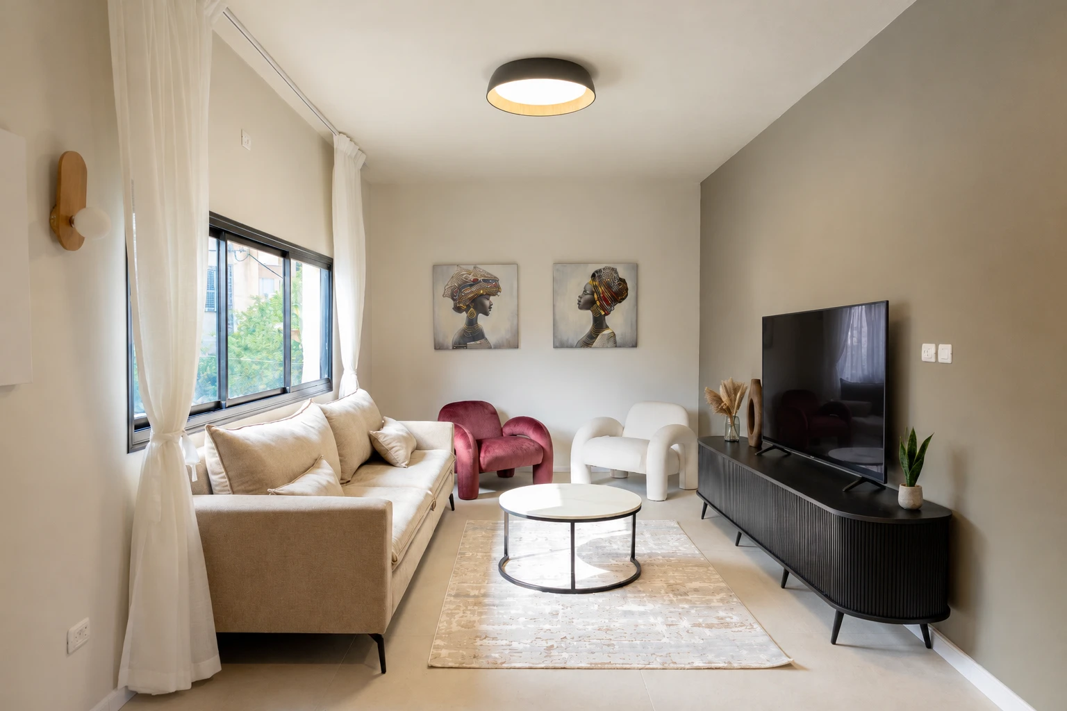 The living room: two portrait paintings above the velvet and bouclé armchairs, and a large TV on the console