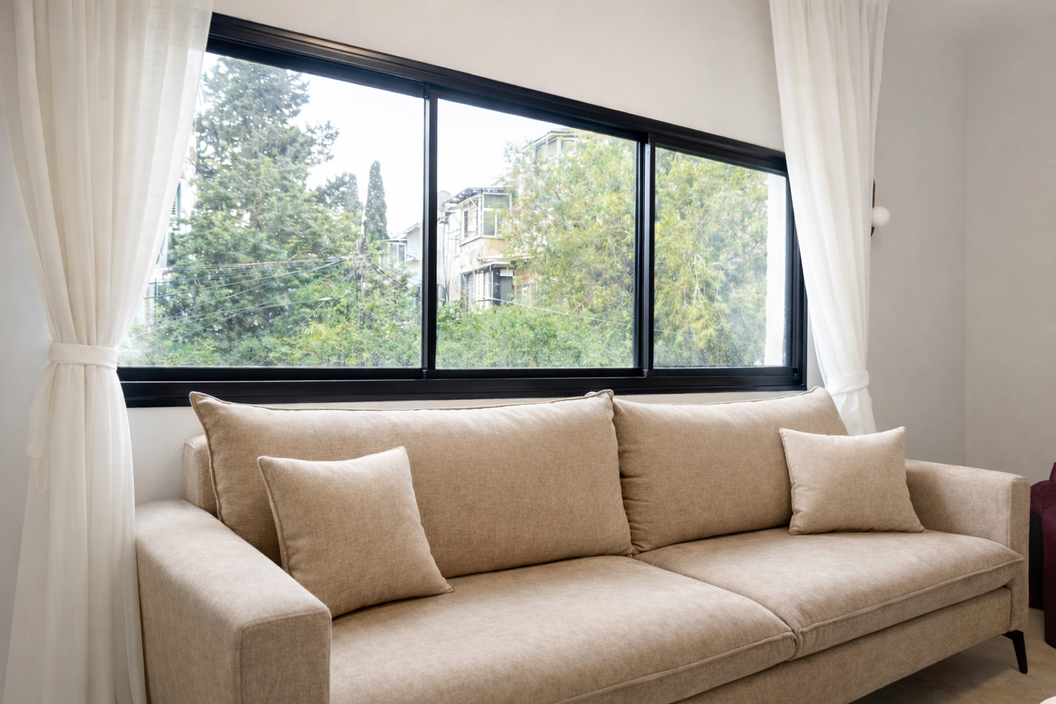 The living room sofa facing a large window onto the trees